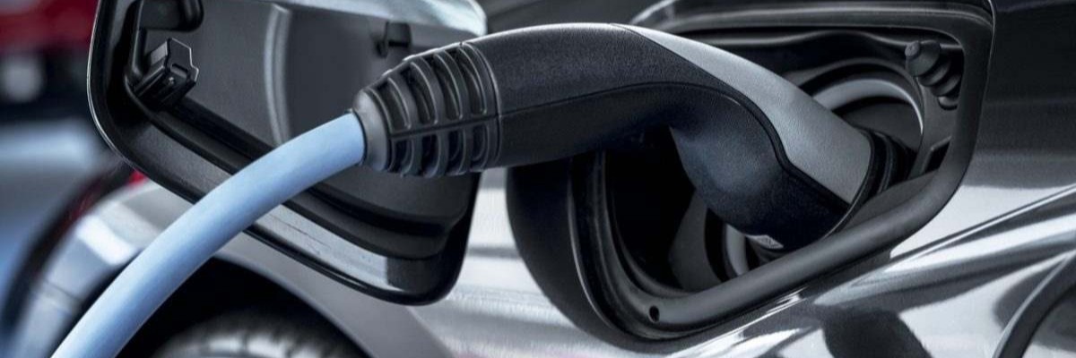 Close-up of an electric vehicle being charged with a blue cable plugged into the charging port.
